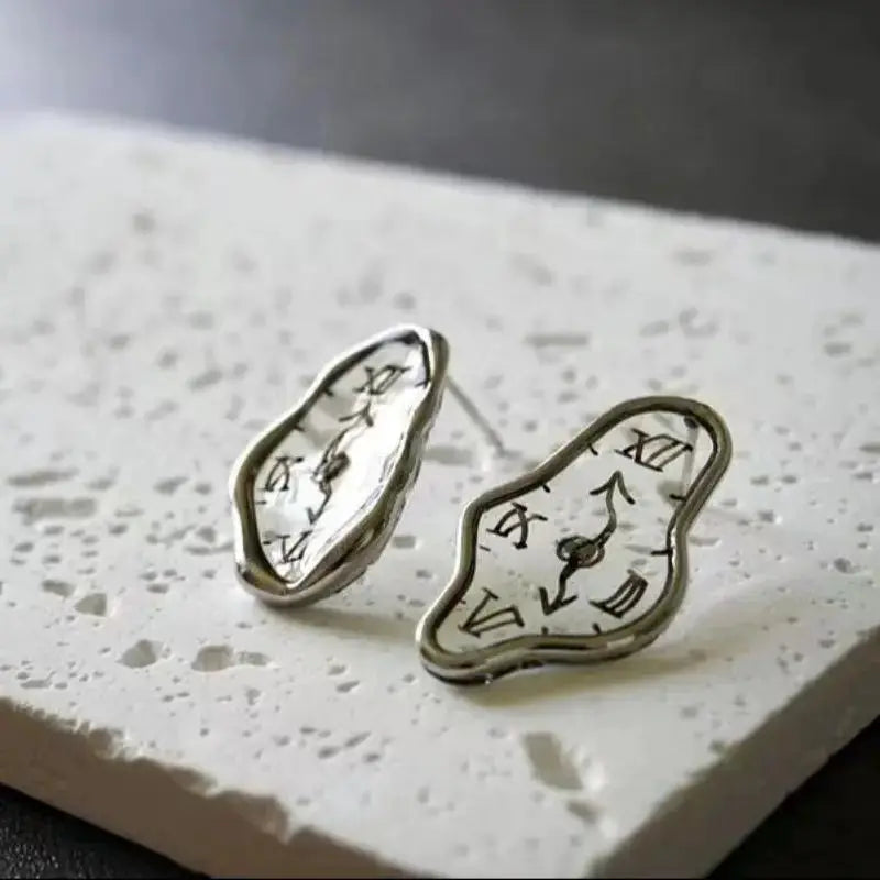 Pair of irregular clock-shaped earrings in silver-tone metal with white clock faces featuring black Roman numerals