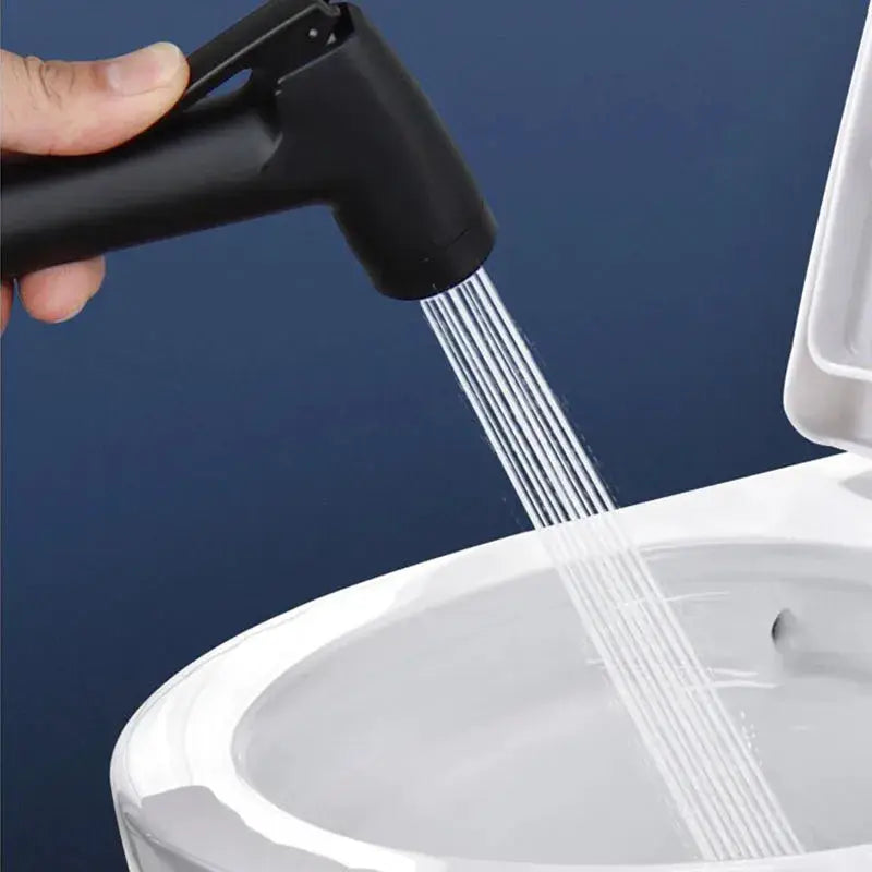 Handheld black bidet spray gun for bathroom, spraying water into toilet bowl