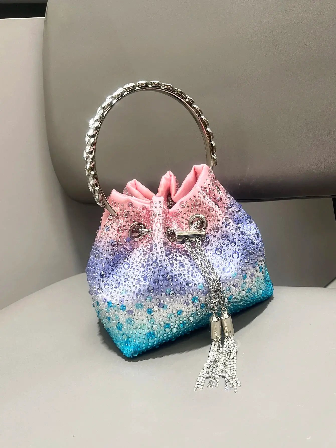 Rhinestone handle evening clutch bag with circular crystal hoop and gradient pink-to-teal beaded body