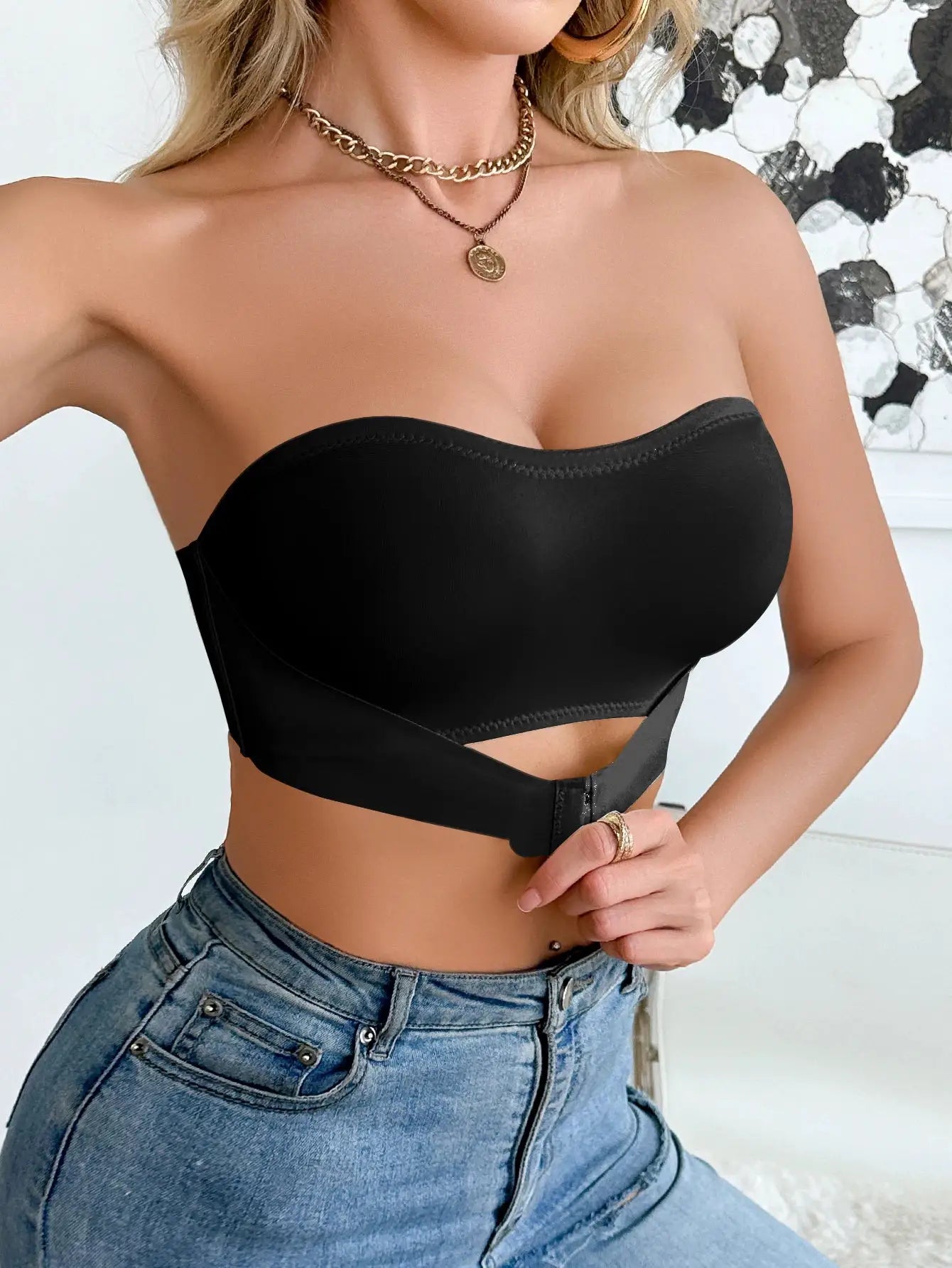 Black strapless wireless bralette with front clasp worn by a woman in jeans