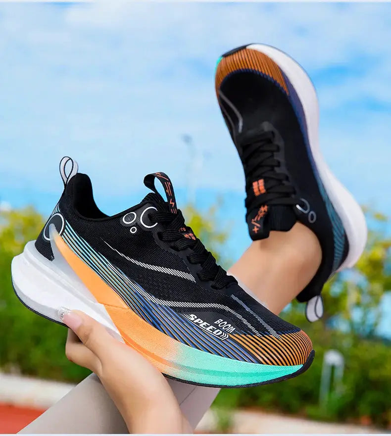 Pair of running shoes in black with multicolor gradient sole from orange to teal, breathable knit upper, white midsole.