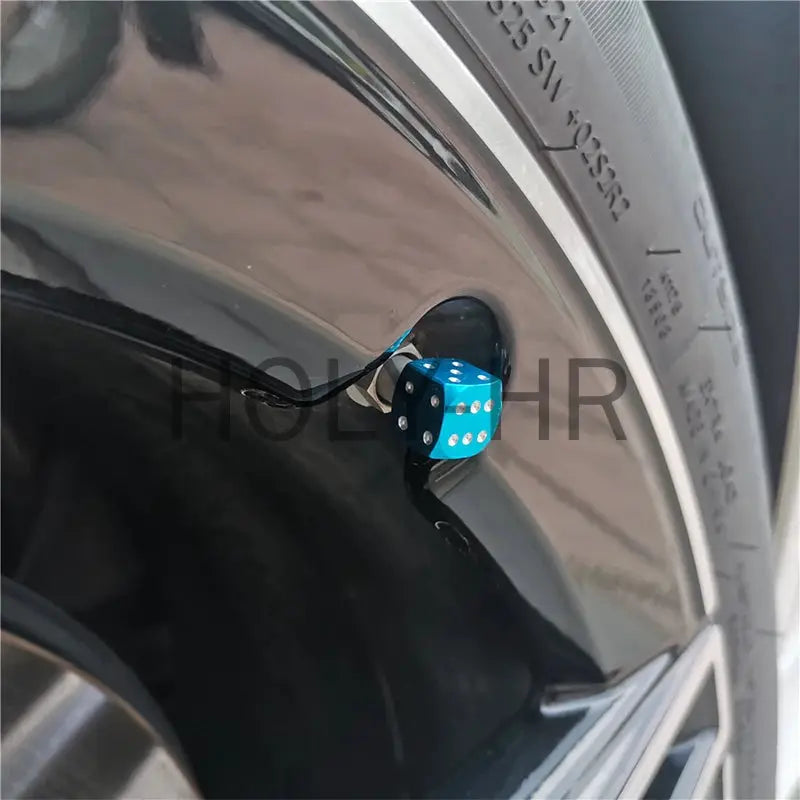 Blue aluminum dice tire valve cap installed on car wheel valve stem; dustproof cap