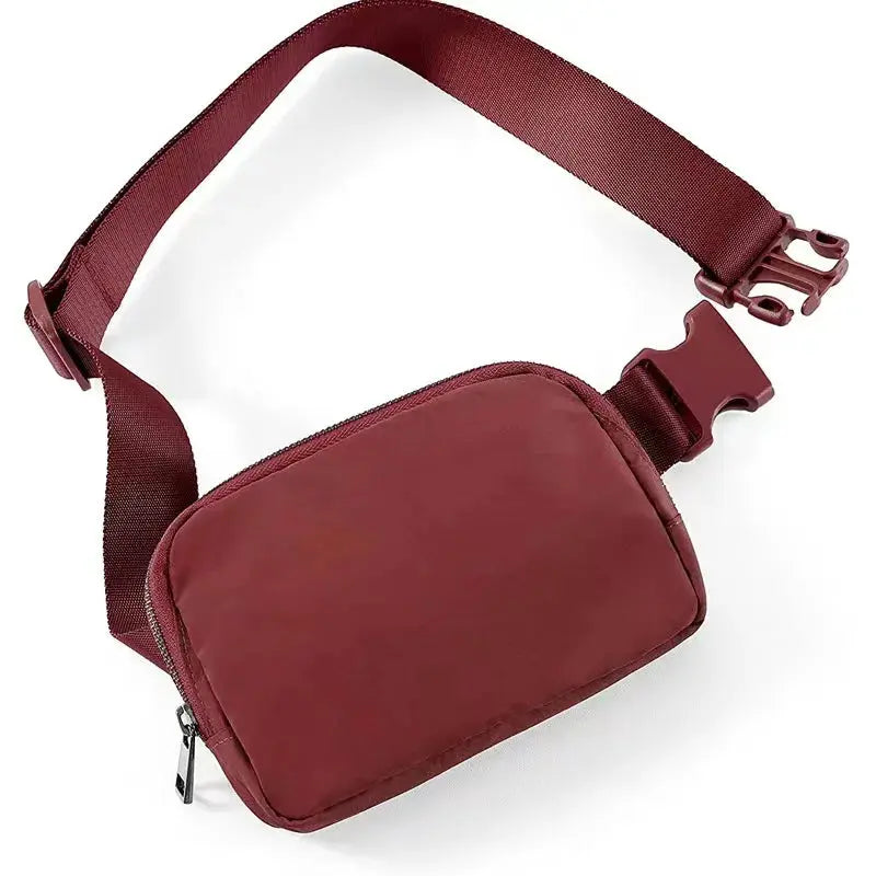 Fanny pack waist bag in burgundy nylon with zipper, adjustable strap and quick-release buckle.