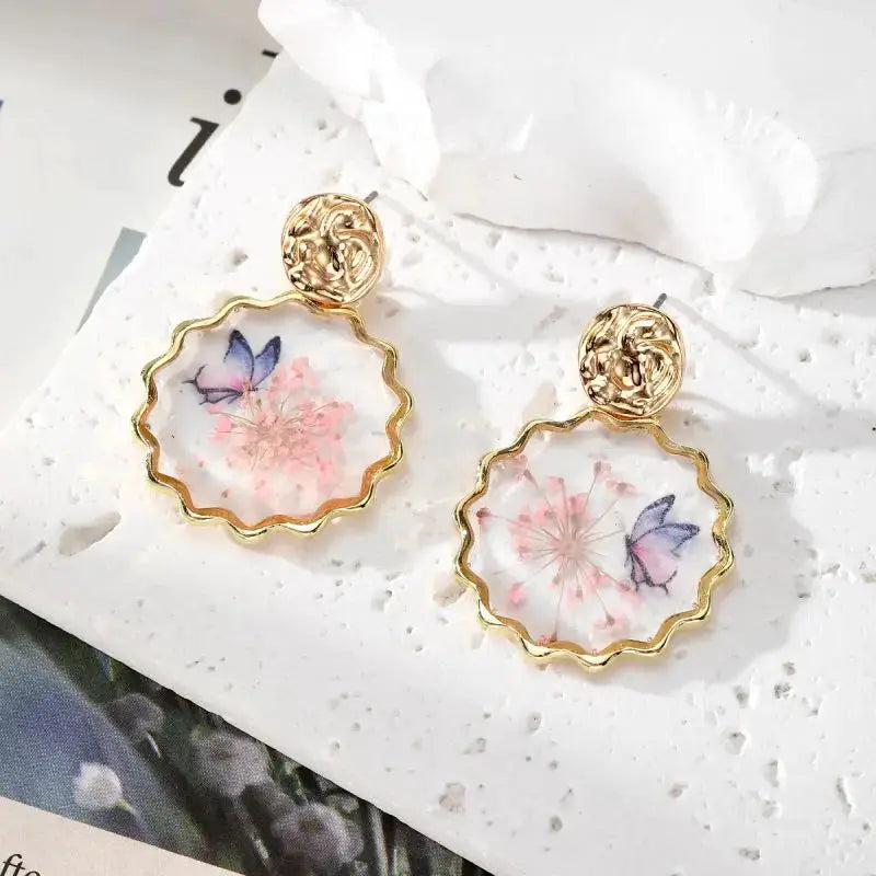 Pair of gold-tone epoxy resin dangle earrings with scalloped hoops and pressed pink flowers