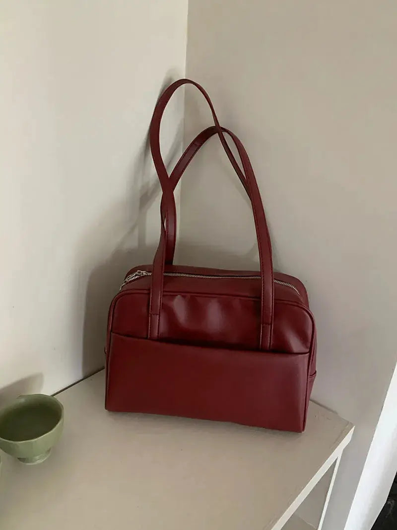 Tote bag, red leather-style with dual handles, top zipper closure and front pocket.