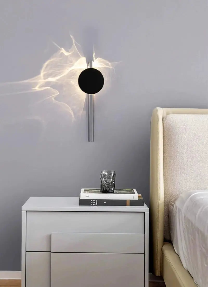 Modern LED wall light with black circular disc on a stainless steel wall sconce for bedroom.