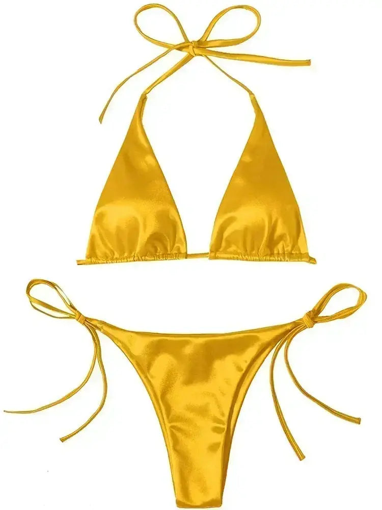 Bikini set by Simples Market in metallic gold satin, halter top two-piece with high-cut bottoms.