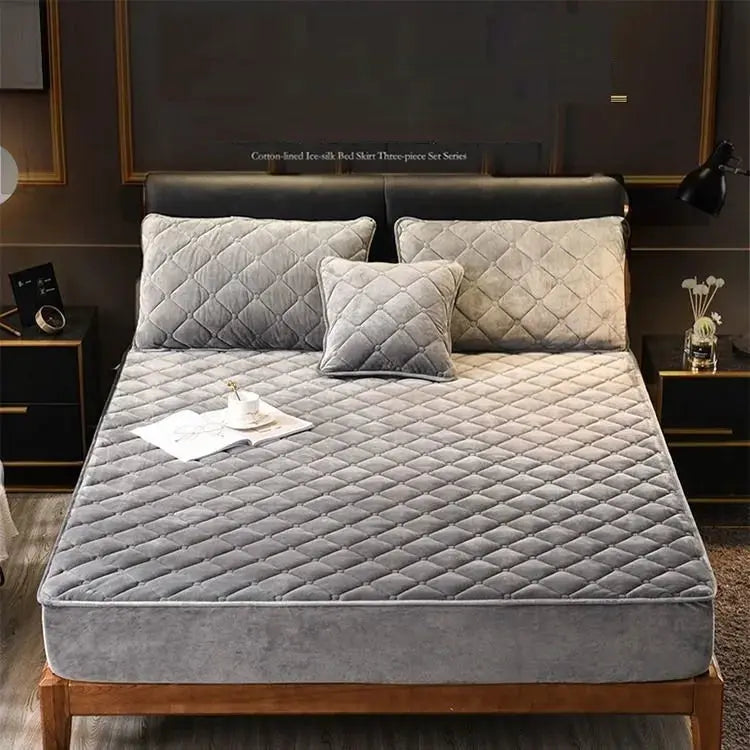 Plush quilted mattress cover in crystal velvet by Simples Market on a bed with three gray quilted pillows