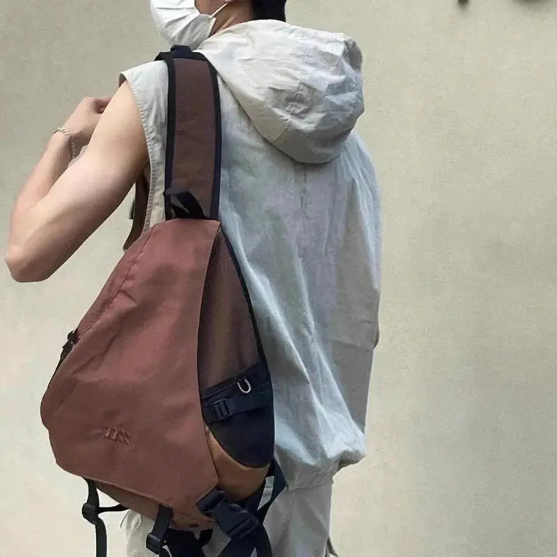 Y2k portable light nylon crossbody bag in brown with black trim, worn as a unisex travel chest pack.