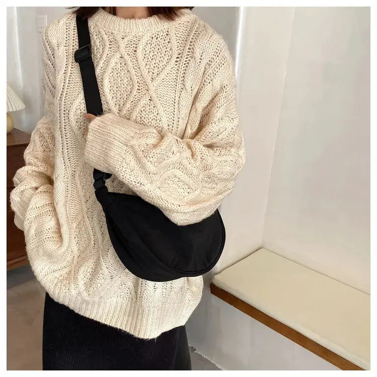 Casual nylon hobo crossbody bag in black with adjustable strap worn over a cream knit sweater.