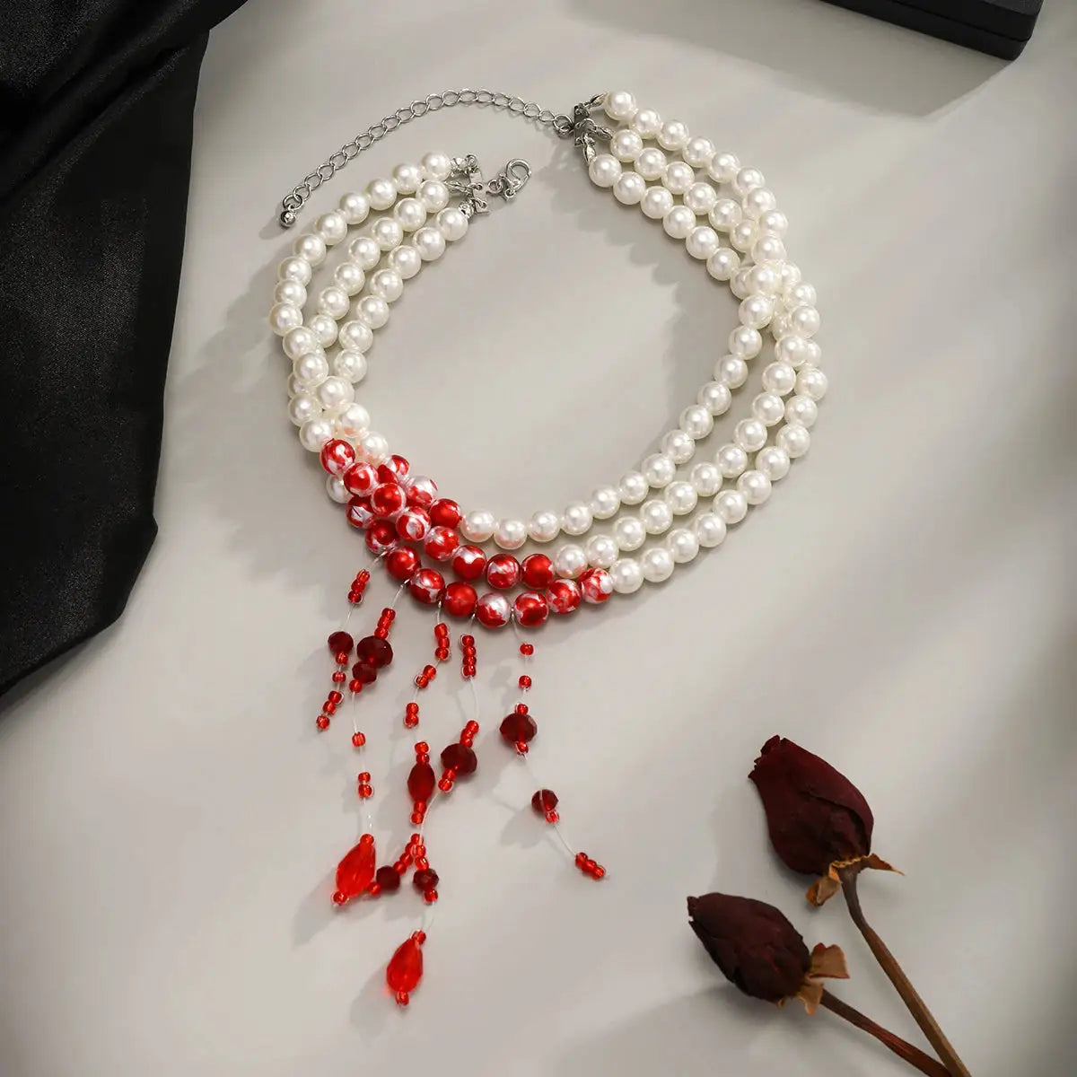 Three-strand imitation pearl tassel necklace with red bead drops