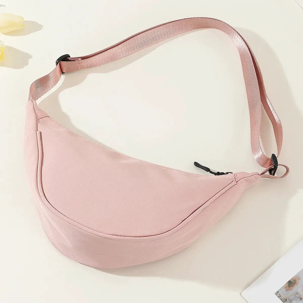 Pink nylon dumpling bag with adjustable pink strap, compact crossbody shoulder bag.
