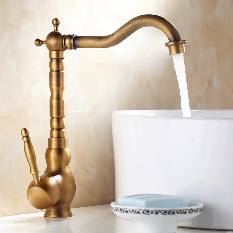 Antique brass bathroom faucet with rotating spout by Simples Market over white washbasin.