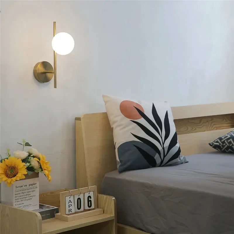 Modern golden LED wall lamp with milky glass globe for bedside, includes G9 bulbs.
