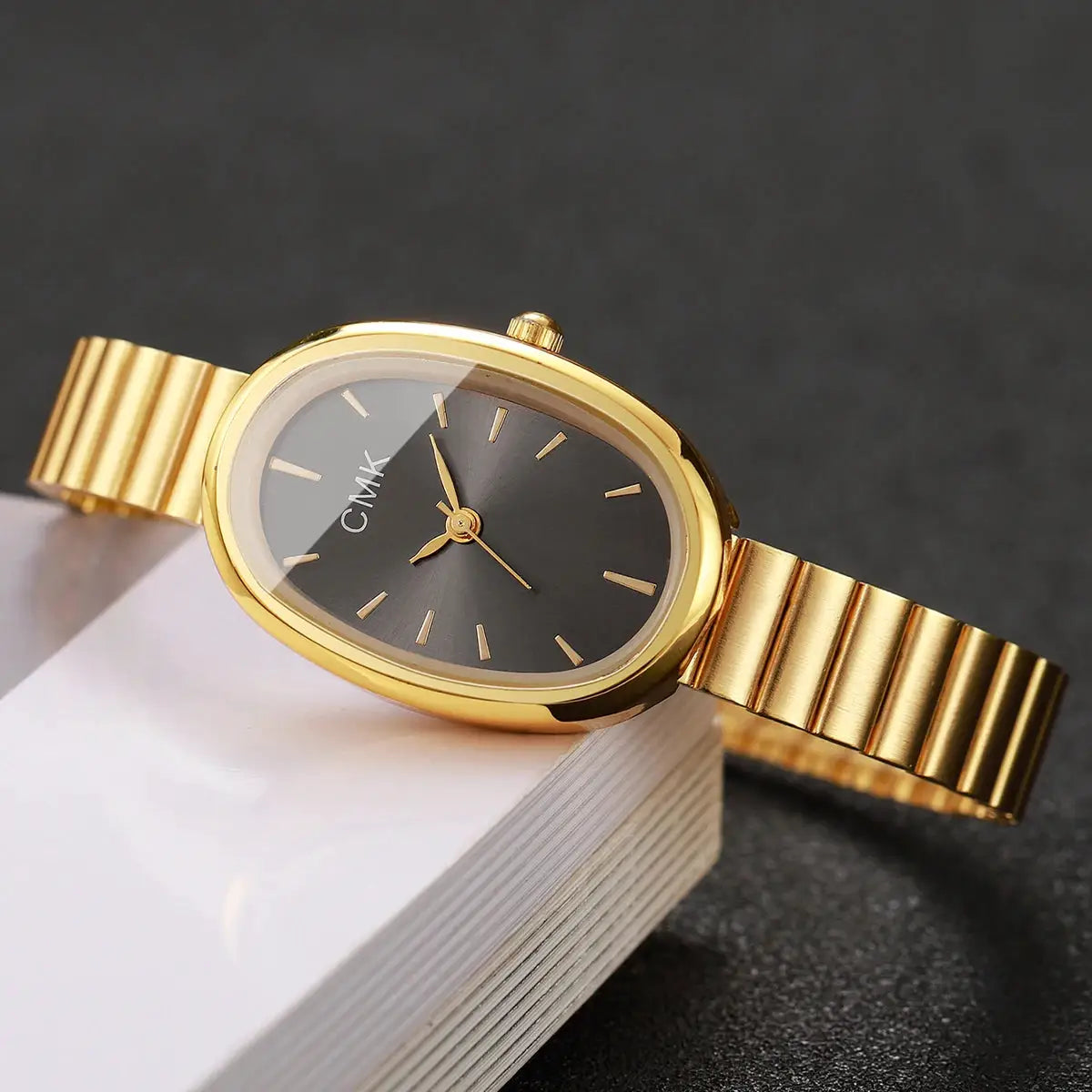 Women's gold-tone oval-dial wristwatch with slim gold bracelet and black dial, CMK logo