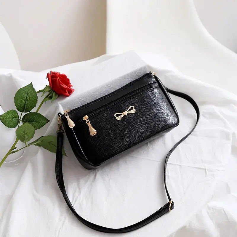 PU synthetic leather black shoulder crossbody bag with alligator-pattern flap and gold bow accent Simples Market