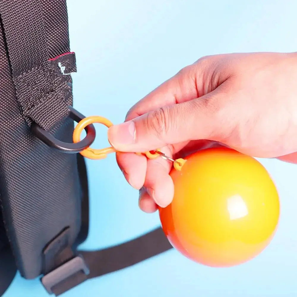 Orange-yellow pocket ball keychain attached to a backpack strap