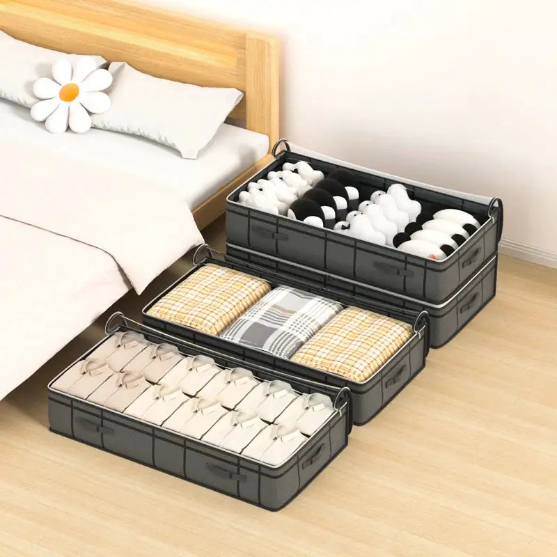 Three gray fabric under-bed storage bags with handles, filled with quilts and clothes for bedroom organization.