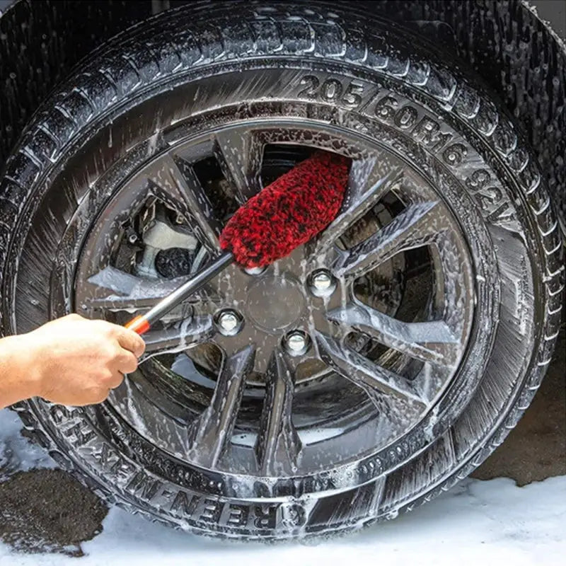 Car wheel detailing brush, bendable shaft with red bristles cleaning a car rim