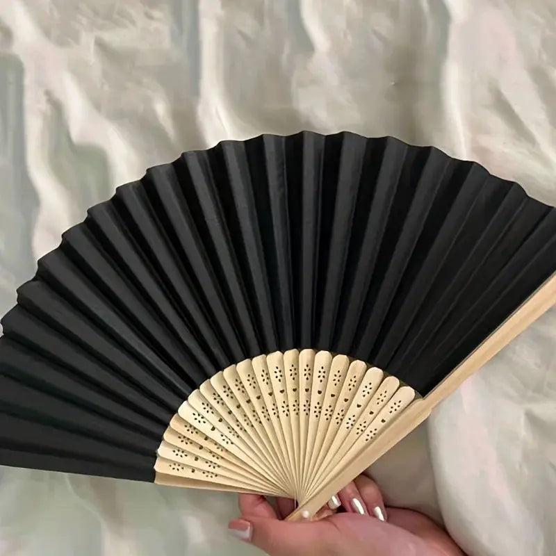 Hand folding fan with black fabric panels and beige bamboo ribs