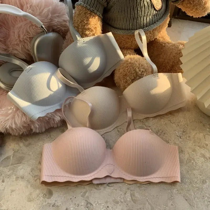 Three ribbed seamless bras in gray, light gray, and pink; non-wire bralettes laid out for display.