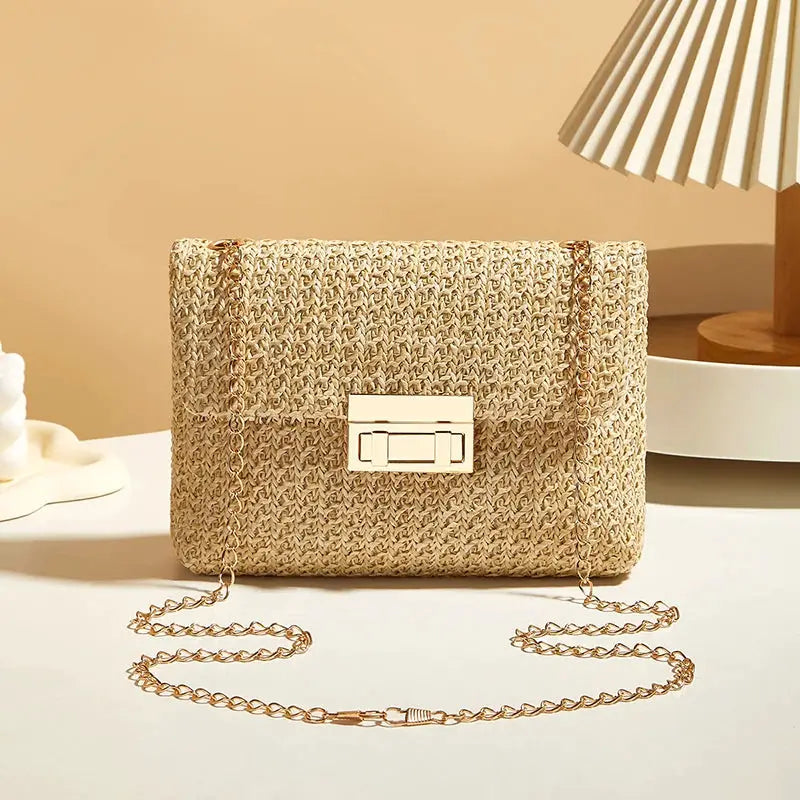 Crossbody bag for women with a gold-tone chain strap and woven straw exterior in natural beige.