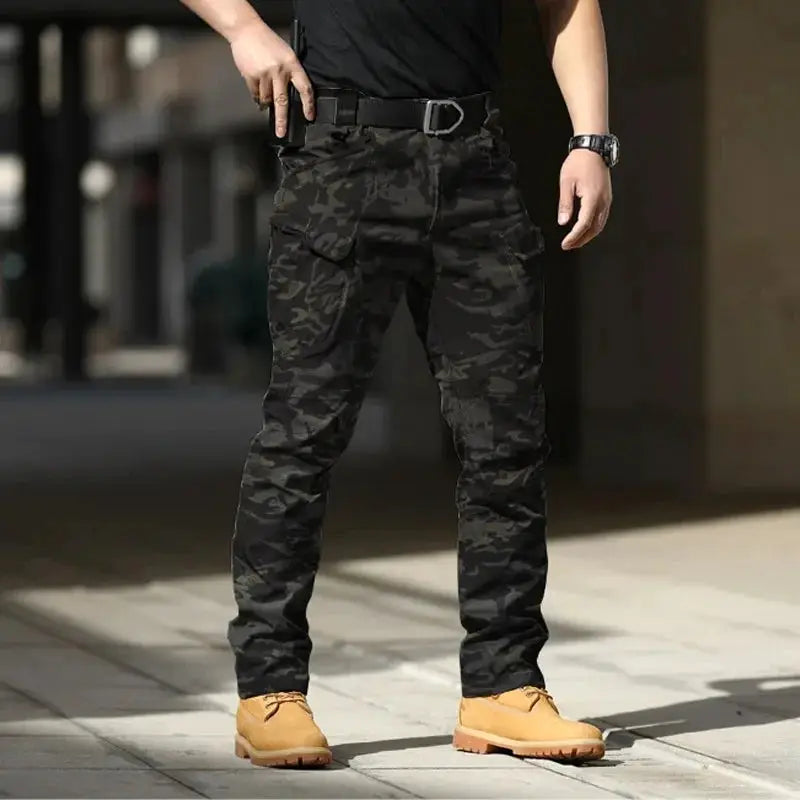 Men's tactical cargo pants in black camouflage softshell with stretchy fabric and multiple pockets.