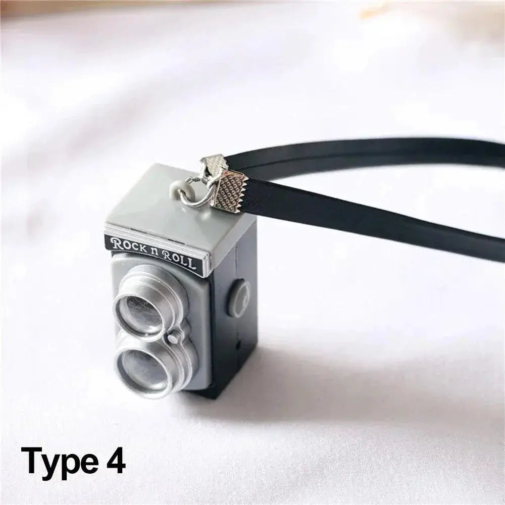 Dollhouse miniature camera with black strap, gray metal body