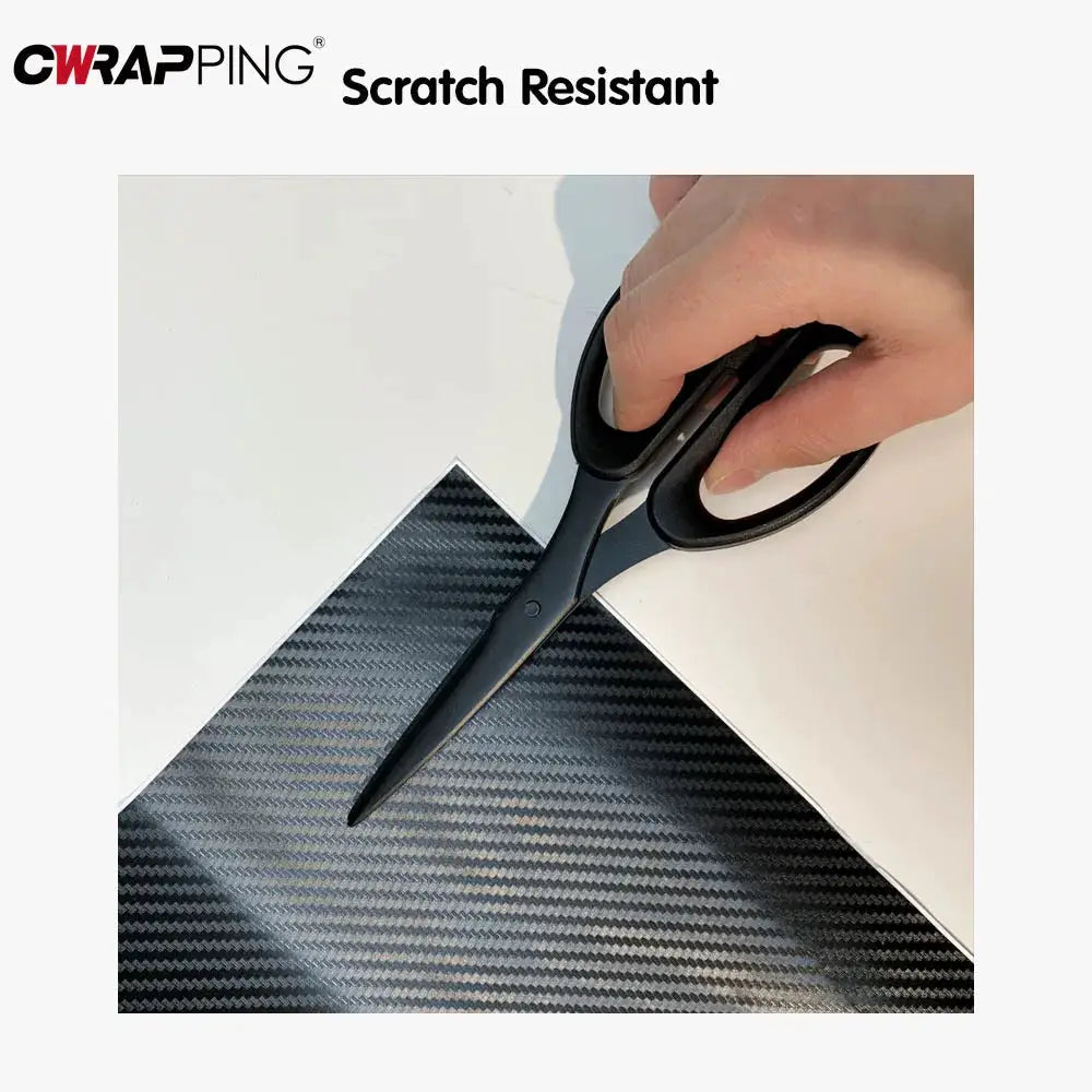 2D-9D carbon fiber vinyl wrap sheet cut with scissors, showing a black carbon fiber pattern.