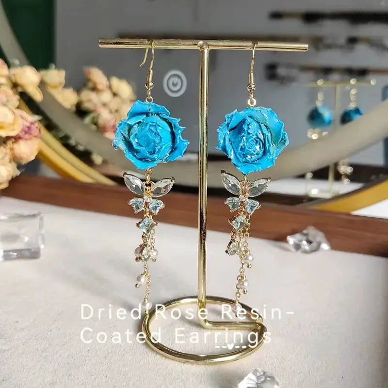 Pair of blue rose epoxy resin long earrings with crystal accents on gold-tone chains