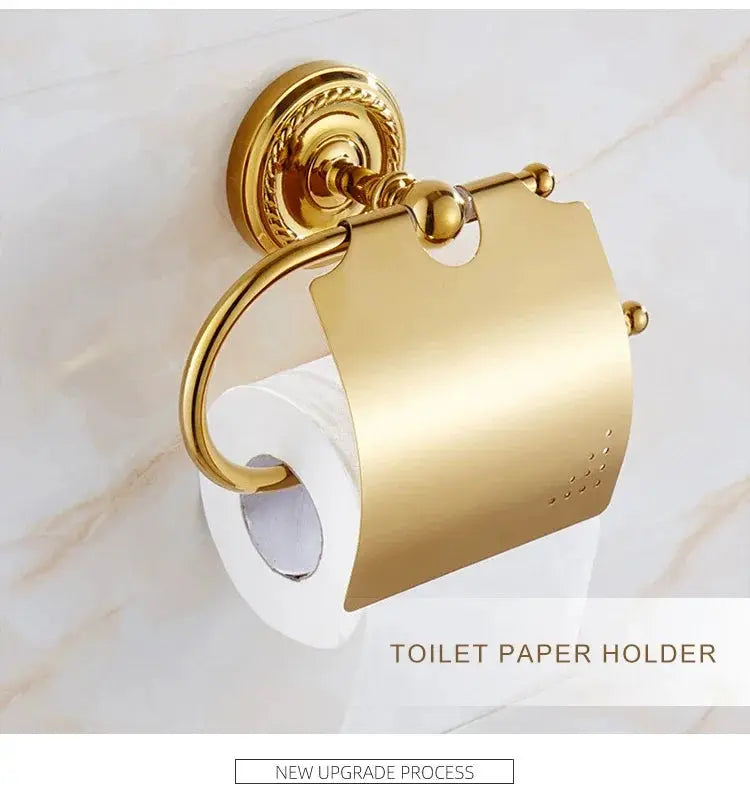 Gold brass toilet paper holder with ornate wall mount on marble tile