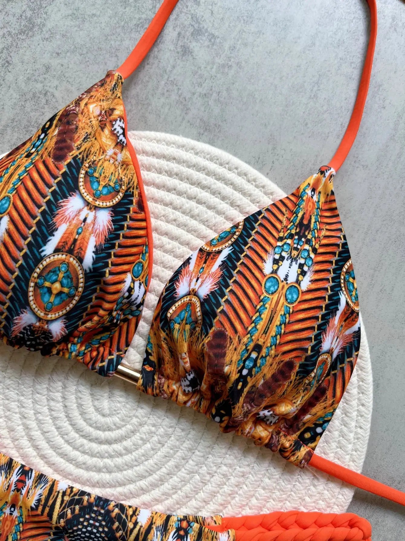 Two-piece halter bikini set with high-cut bottoms in vibrant tribal print and orange straps