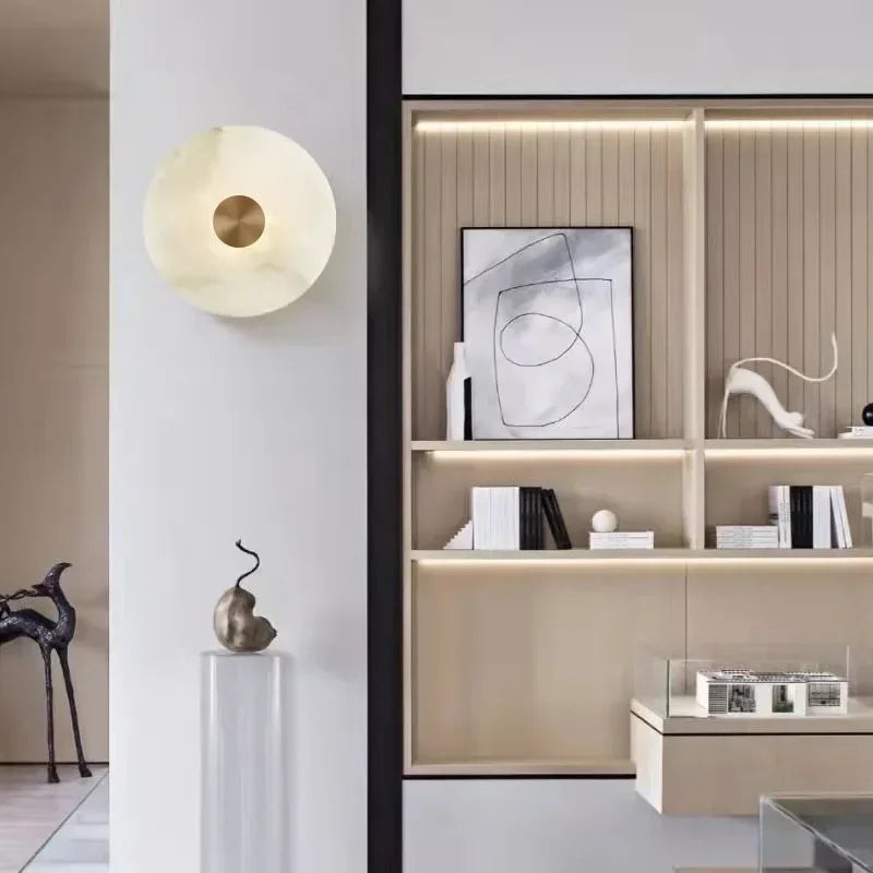 Luxury Spanish natural marble wall lamp with copper center mounted on a white wall beside beige shelving unit