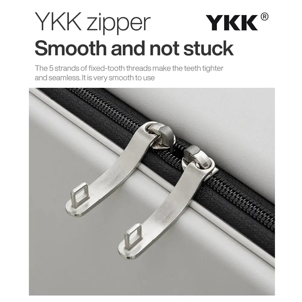 Carry-on suitcase with dual metal zipper pulls on a light gray shell, YKK zipper.