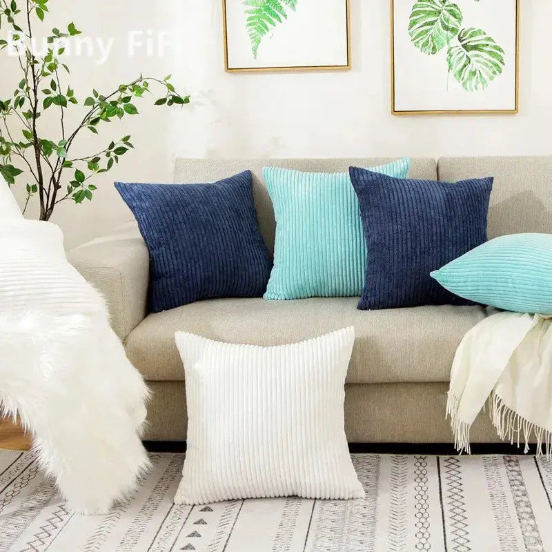 Corduroy striped cushion covers; five cushions in navy, teal and white on a beige living room sofa.