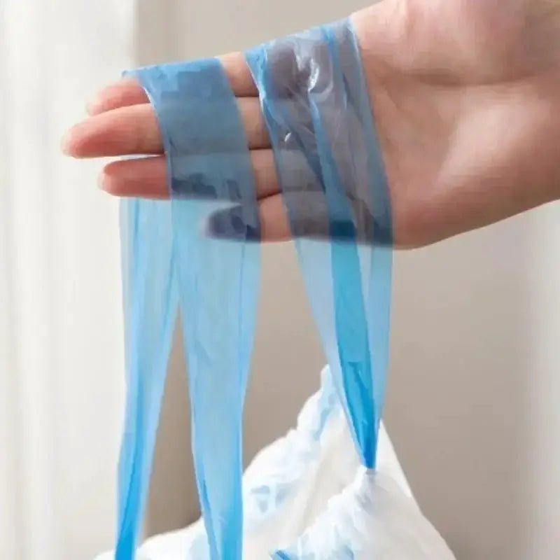 Blue drawstring garbage bag held by hand, transparent plastic with long tie handles.