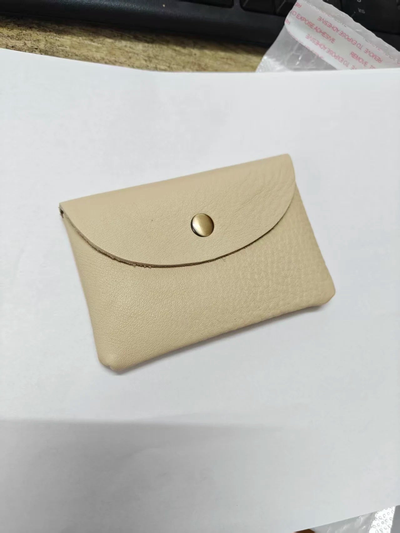 Genuine leather card holder in beige with envelope-style flap and brass snap.