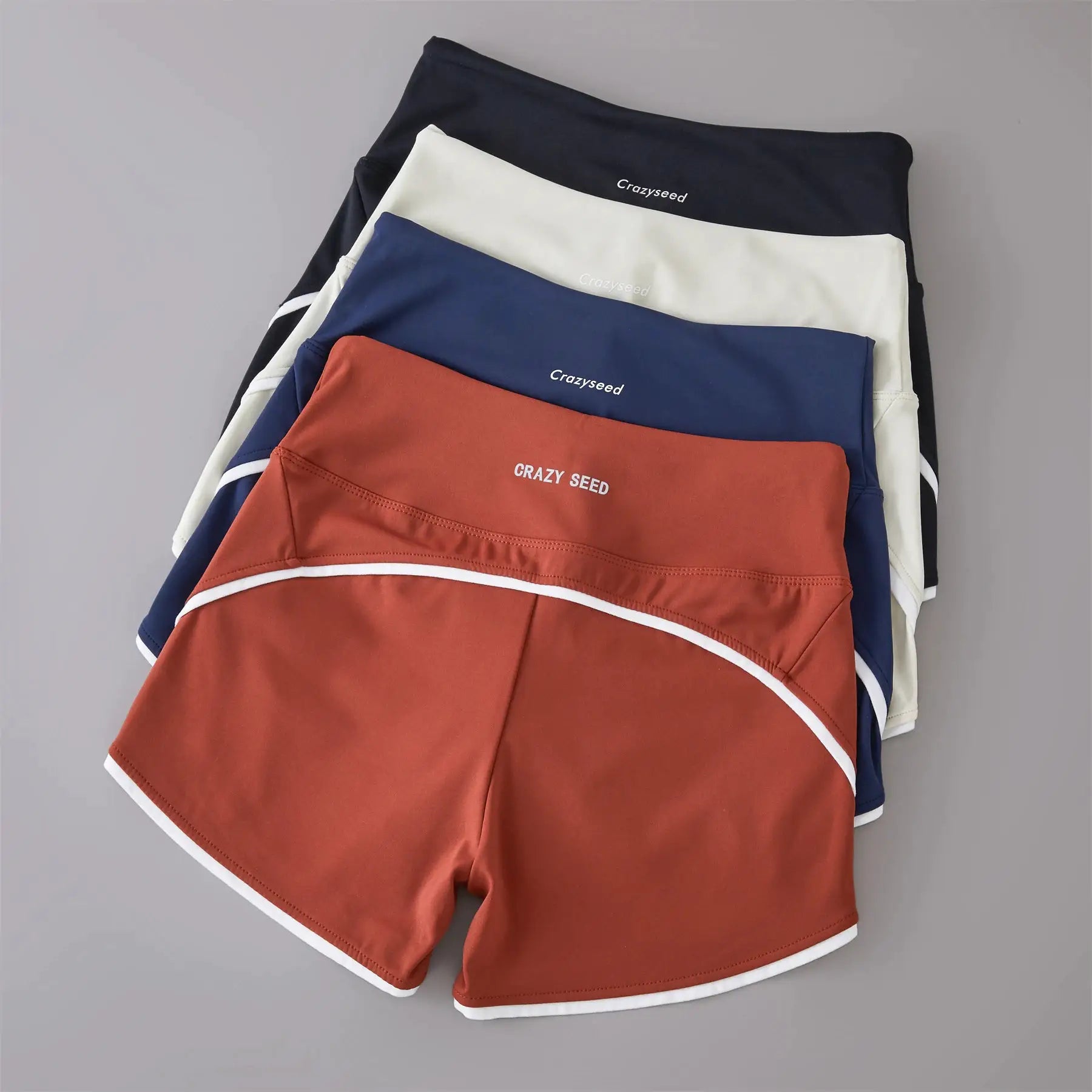 Five color-contrast high-waist sports shorts by Crazyseed (Simples Market) in black, white, navy, peach, and rust.