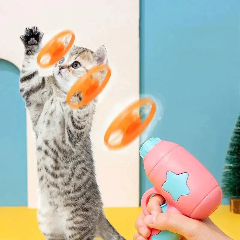 Simples Market interactive cat launcher toy, pink gun with blue star, firing three orange discs toward kitten