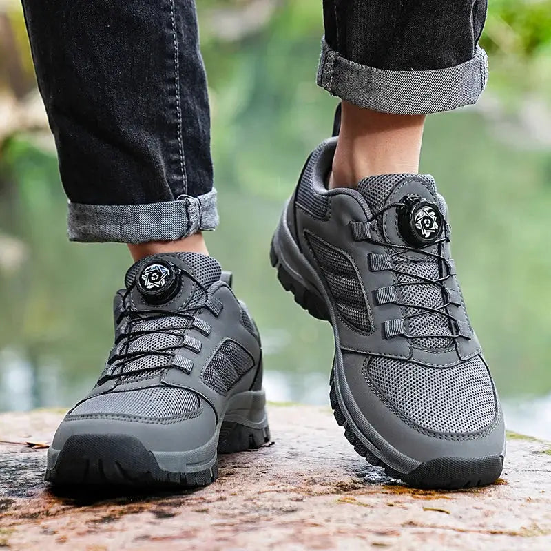 Pair of men's gray outdoor hiking shoes with rotating dial, mesh upper, rugged anti-slip sole.