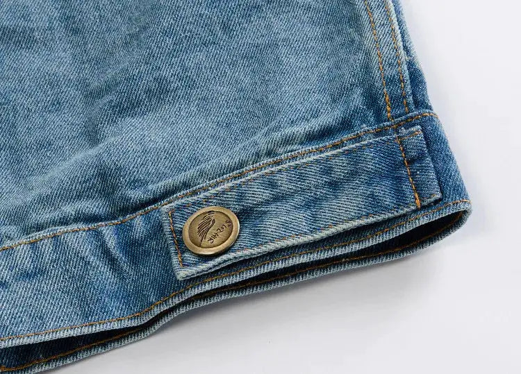 Denim jacket sleeve cuff in light blue with brass button and visible stitching