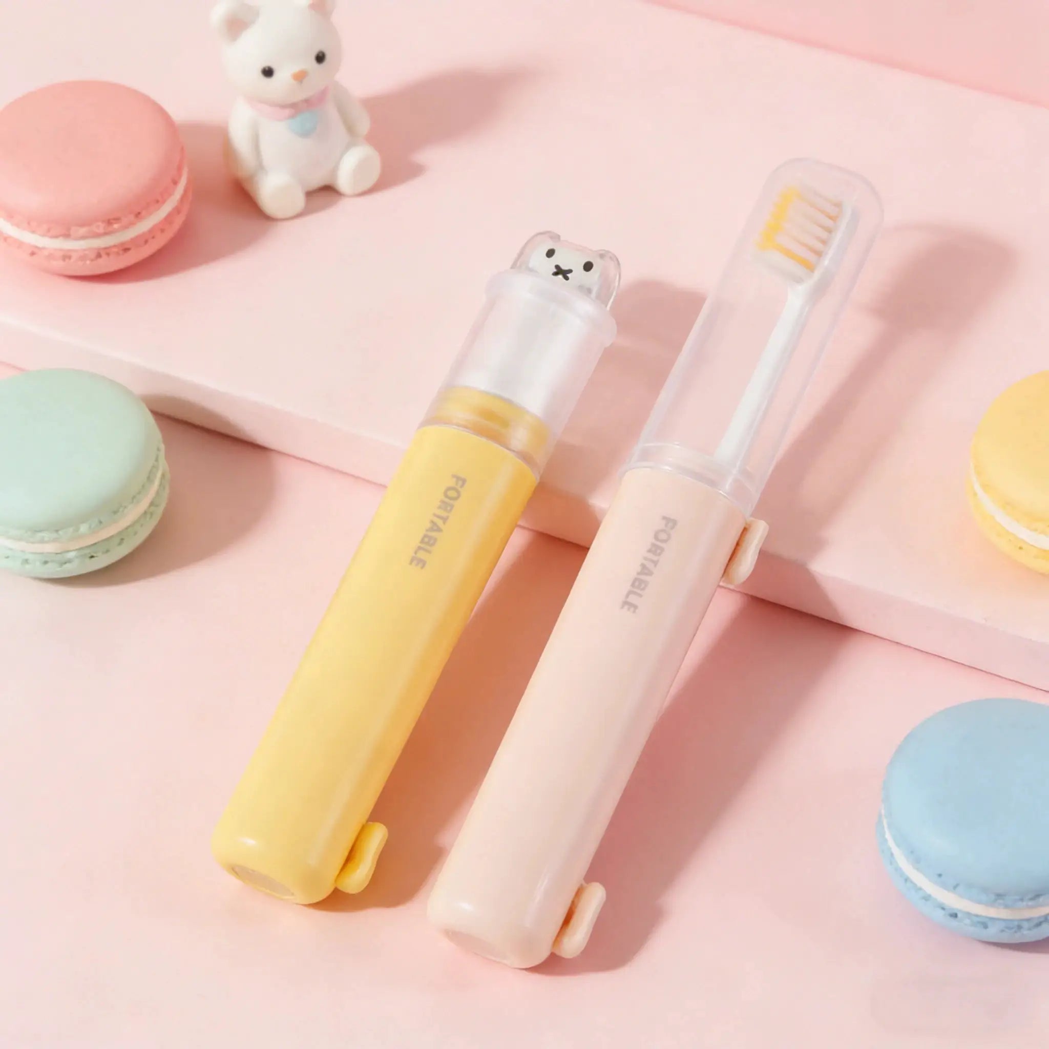 Two pastel travel toothbrushes with bear lids; 2-pack in yellow and white, foldable with toothpaste storage
