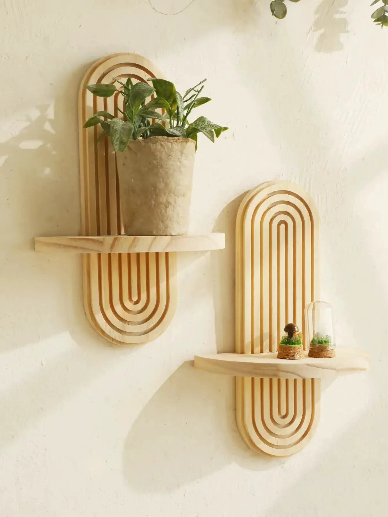 Three-piece boho geometric wooden wall shelf set in natural finish with a potted plant on a rustic white wall