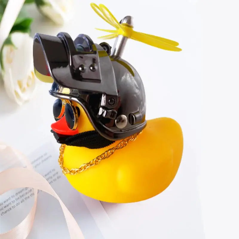 Rubber duck car décor: yellow duck wearing a black motorcycle helmet with a yellow propeller on top and sunglasses