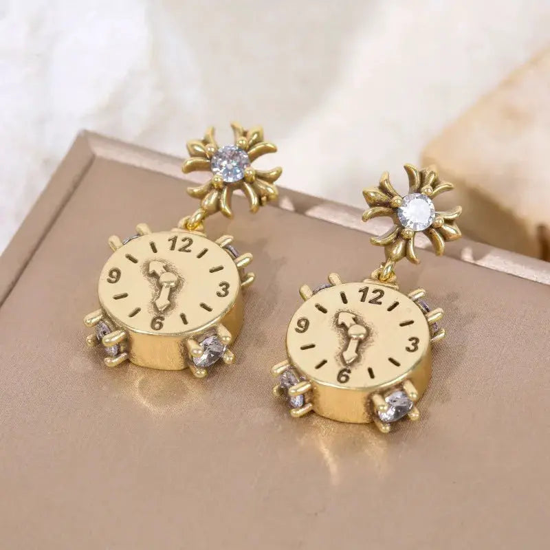 Gold-tone clock earrings pair with crystal accents and flower-top studs by Simples Market