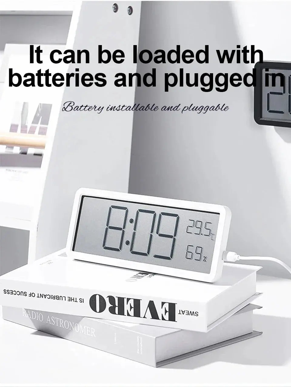 White desktop LCD digital clock displaying 8:09 with temperature 23.5 and humidity 69%, battery powered.