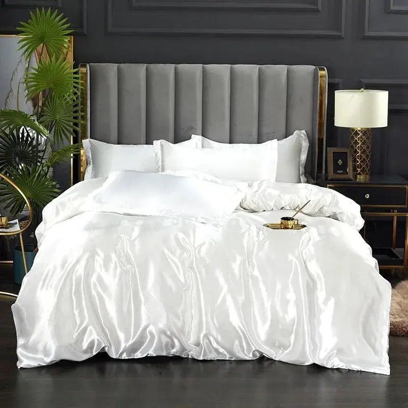 Silk bedding set with duvet cover and pillowcases in white satin on a gray upholstered bed