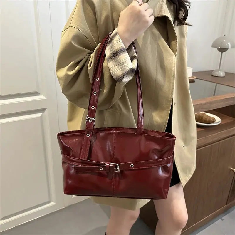 Red leather handbag with belt-buckle front, top handles and adjustable shoulder strap; soft Korean-style casual bag