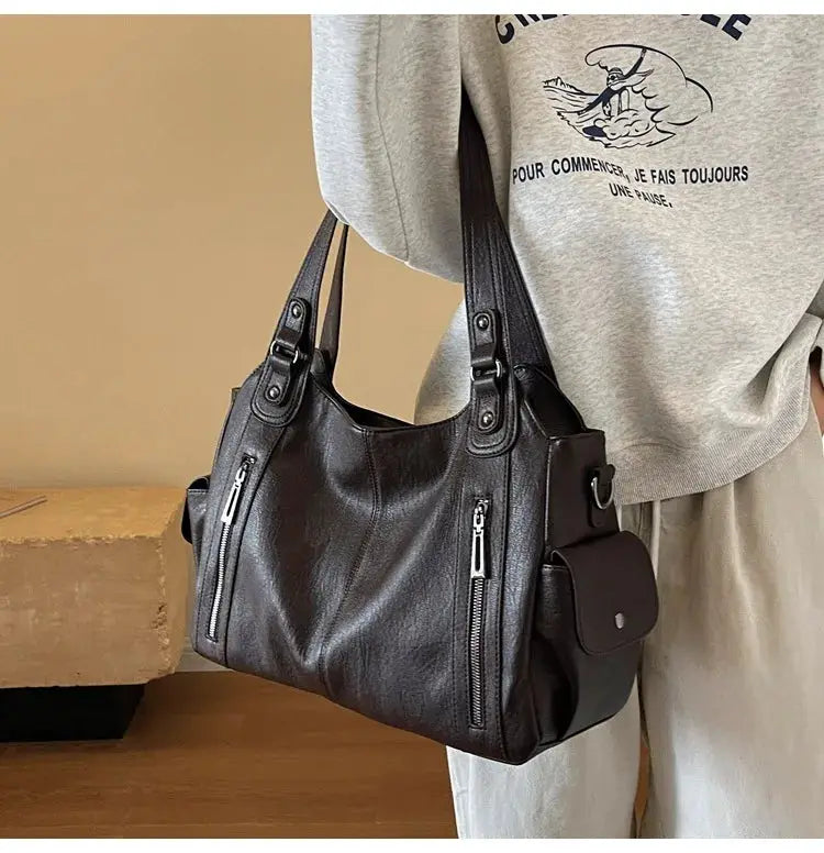 Soft interior compartment shoulder bag in black PU leather with silver zippers and side pocket
