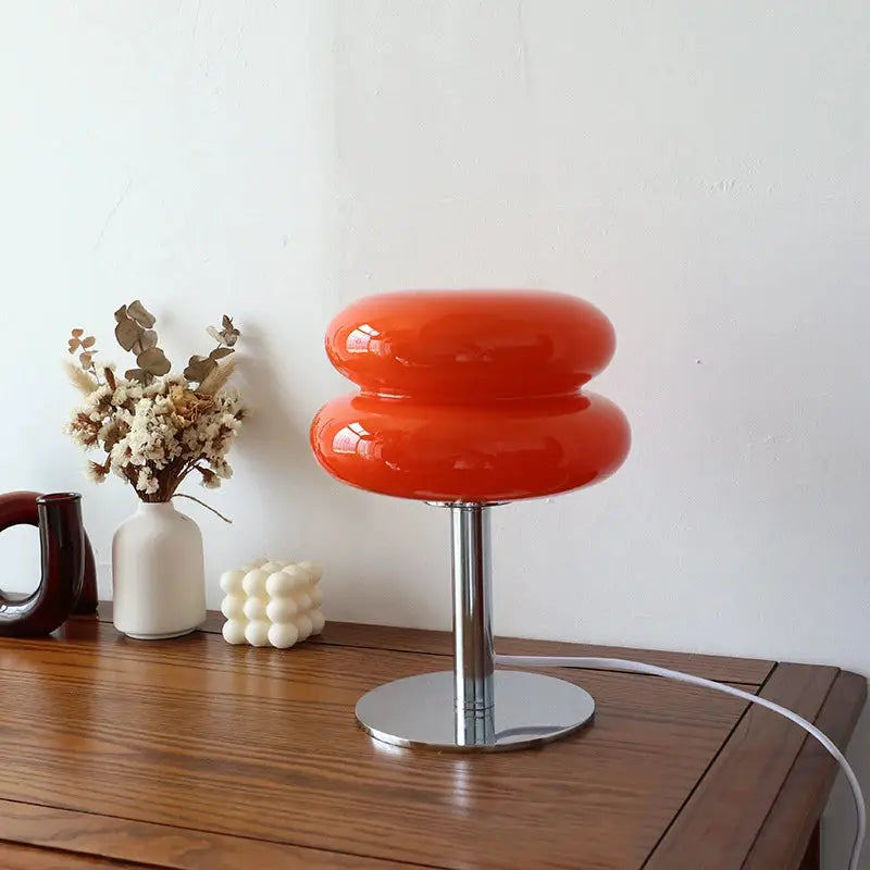 Macaron glass table lamp, orange double-stack shade with chrome stem and round base on a wooden desk